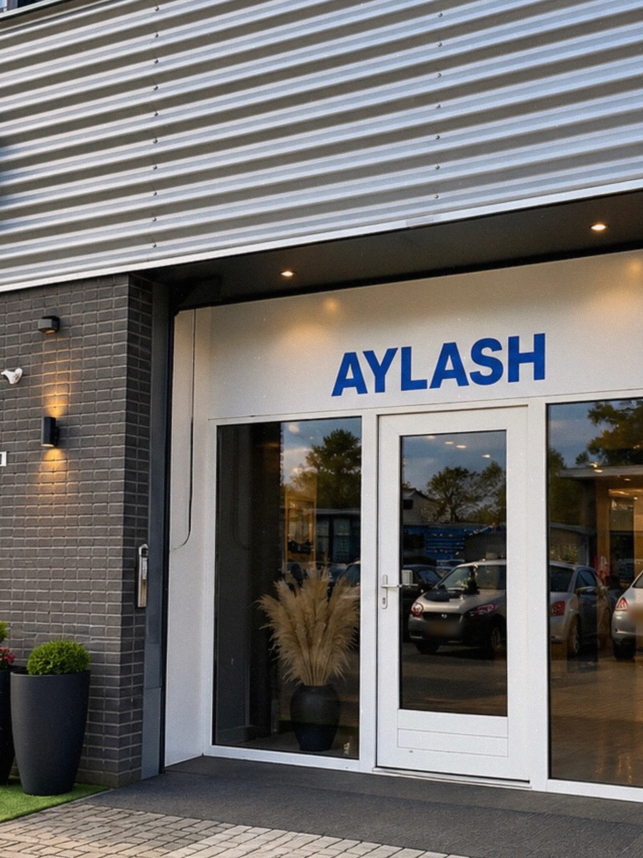 De ingang van Aylash met het blauwe AYLASH-bord boven de glazen deur
